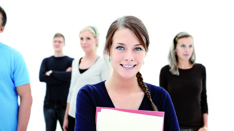 Mehrere Personen stehen hintereinander, ganz vorne eine junge Frau mit einer Mappe in der Hand