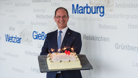 Regierungspräsident Dr. Ullrich hält eine Torte zum 40ten Jubiläum in der Hand