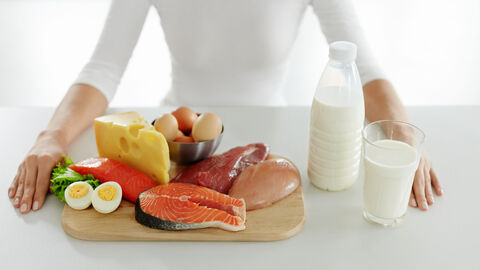 Vor einer Frau stehen tierische Lebensmittel auf einem Tisch. Vor einer Frau stehen tierische Lebensmittel auf einem Tisch.