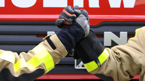 Zwei Feuerwehrleute geben sich die Hand. Zwei Feuerwehrleute geben sich die Hand.