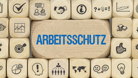 Das Wort Arbeitsschutz steht zwischen vielen Würfeln, auf denen Symbole aus dem Arbeitsleben abgebildet sind.