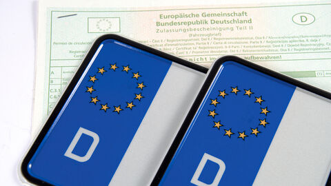 KFZ-Kennzeichen liegen auf einem Fahrzeugbrief.