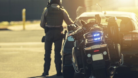 Ein Motorradpolizist hält ein Fahrzeug in einem anderen Staat an.