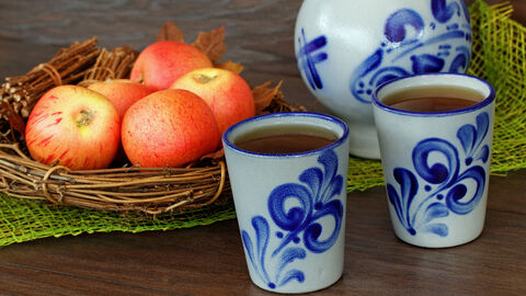 Hessischer Apfelwein im typischen Bembel und Äpfel stehen angerichtet auf einem Tisch.