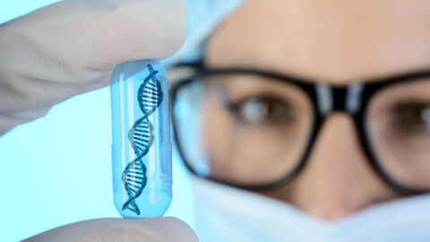 Gentechniker hält Kapsel mit DNA Doppelhelix in der Hand. Gentechniker hält Kapsel mit DNA Doppelhelix in der Hand.