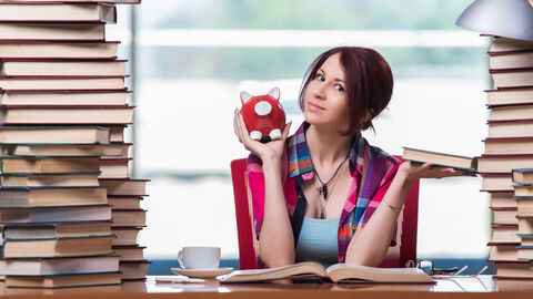 Eine Studentin hält ein Sparschwein in der Hand.