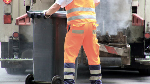 Ein Arbeiter zieht eine Restmülltonne zum Müllwagen. Ein Arbeiter zieht eine Restmülltonne zum Müllwagen.