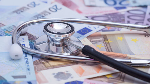 Ein Stethoskop liegt auf Geldscheinen.