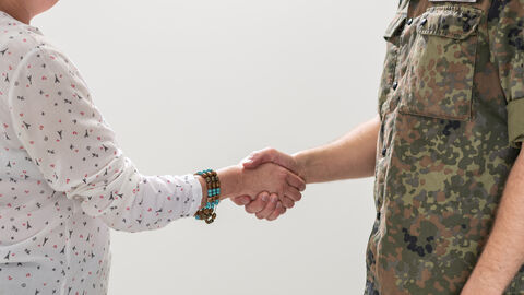 Ein Soldat gibt einer Frau die Hand.