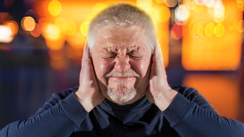 Ein Mann hält sich die Ohren zu.