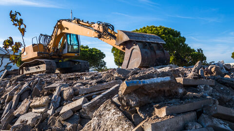 Ein Bagger steht auf Bau- und Gewerbeabfällen.