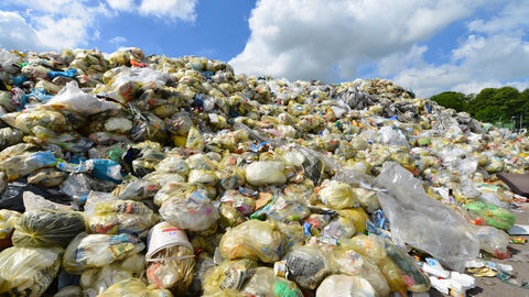 Ein großer Berg aus gefüllten gelben Säcken reicht bis zum Himmel.