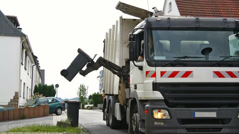 Ein Müllwagen leert eine Restmülltonne.