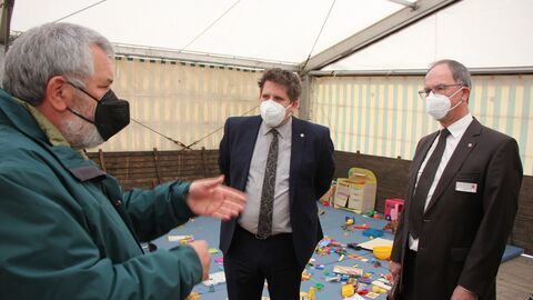 Standortleiter Robert Zwick (RP Gießen), Marian Zachow (Erster Kreisbeigeordneter) und Regierungspräsident Dr. Christoph Ullrich in der Spielecke für Kinder in der Notunterkunft in Cölbe.