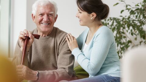 Vereinbarkeit von Familie und Beruf Älterer Mann sitzt mit  jüngerer Frau auf einem Sofa