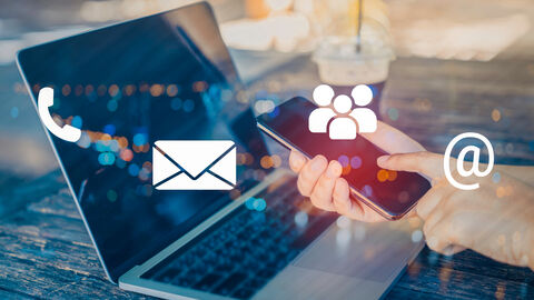 Eine Hand die ein Handy vor einen Laptop hält