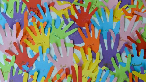 Kinder haben Hände aus buntem Papier ausgeschnitten und ihre Namen darauf geschrieben.