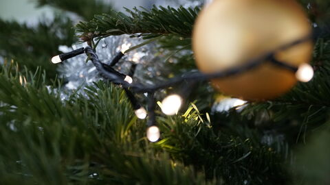 Nahaufnahme eines Weihnachtsbaums mit Lichterkette und Kugel