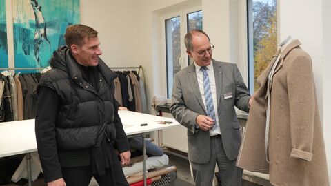 Frank Galfe (Inhaber Geschwister Galfe/links) und Dr. Christoph Ullrich (Regierungspräsident) begutachten einen in Alsfeld gefertigten Mantel.
