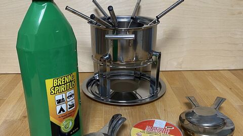 Ein Fonduetopf mit Rechauds, Brennpaste und Spiritus davor