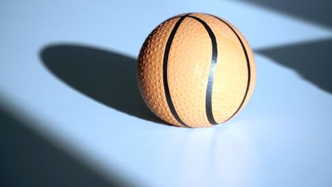 Ein kleiner Basketball, der auf einem Tisch liegt und einen Schatten wirft