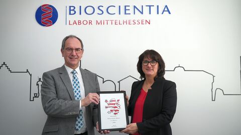 Regierungspräsident Dr. Christoph Ullrich (links) übergibt die Hessenkachel an Andrea Debus, die Geschäftsführerin des Bioscientia Labors Mittelhessen am Standort in Gießen. 