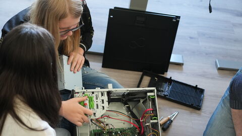 Zwei Jugendliche schauen in das Innere eines Computers