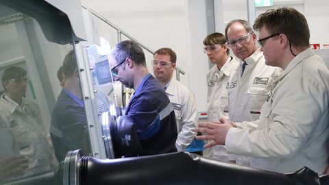 Regierungspräsident Dr. Christoph Ullrich und weitere Männer schauen einem Mitarbeiter bei der Arbeit zu.