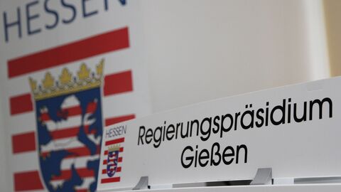 Ein Schild mit dem Schriftzug Regierungspräsidium Gießen auf einem Rednerpult, dahinter das Hessen-Wappen