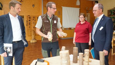 Jugendwaldheimleiter David Menke (2.v.l.) und seine Stellvertreterin Lena Schlotzer (2.v.r.) erläutern Regierungspräsident Dr. Christoph Ullrich und Bürgermeister Dr. Johannes Hanisch (l.) die Vorgehensweise bei der Fertigung von Holz-Figuren für Wikinger-Schach durch Jugendliche im Jugendwaldheim.