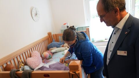 Regierungspräsident Dr. Christoph Ullrich schaut einer Mitarbeiterin des Palliativteams bei der Arbeit über die Schulter