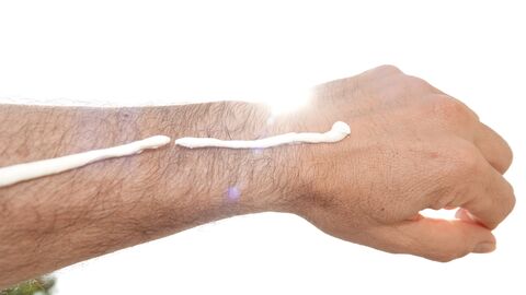 Symbolfoto Ein Arm mit einem Streifen Sonnencreme, der in die Sonne gehalten wird