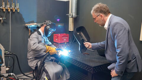 Regierungspräsident Ullrich sitzt an einem Tisch und arbeitet mit einem Schweißgerät. 