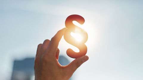 Eine HAnd Held ein Paragrafzeichen in die Höhe.