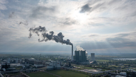 Industrieemissionen Ein Panorama Bild einer Frabrik. Aus dem Schornstein steigt Rauch auf.