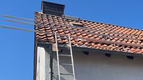 Eine Leiter ist an ein Dach gelehnt, auf dem begonnen wurde, eine PV-Anlage zu montieren
