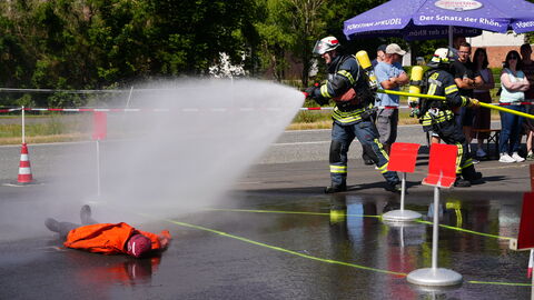 Bezirksfeuerwehrleistungsübungen Feuerwehrleute spritzen Wasser aus einem Strahlrohr.